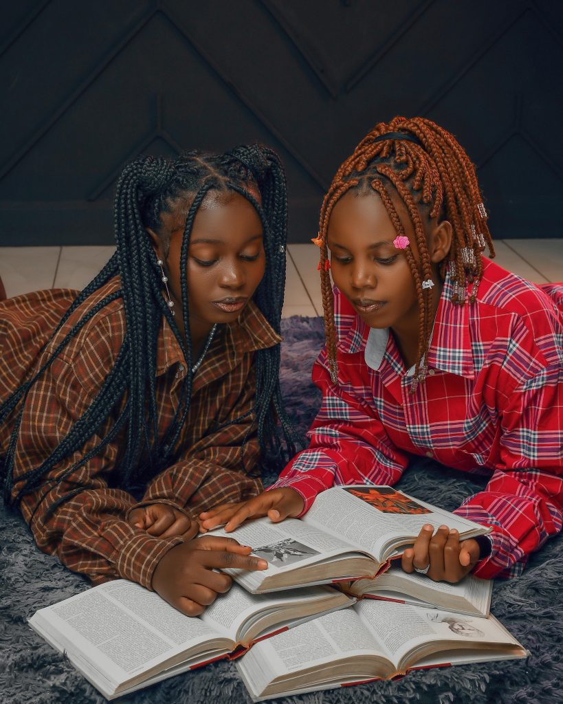 Two girls reading books together in a cozy indoor setting, promoting literacy and friendship.